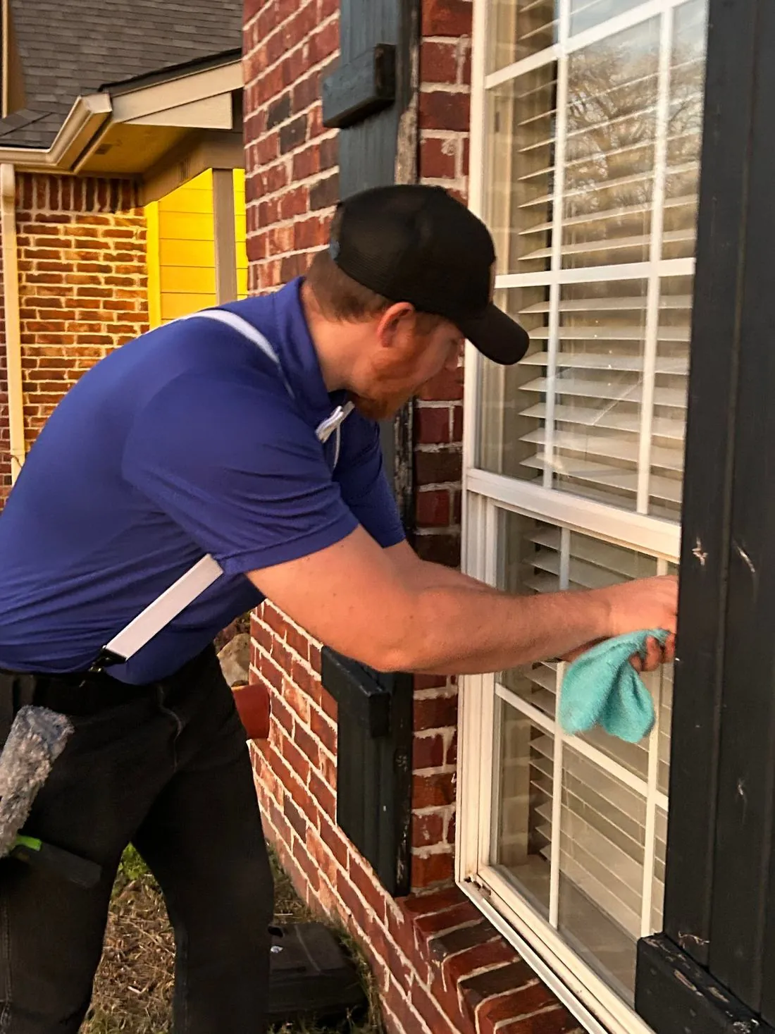 Technician cleaning a window on a brick home