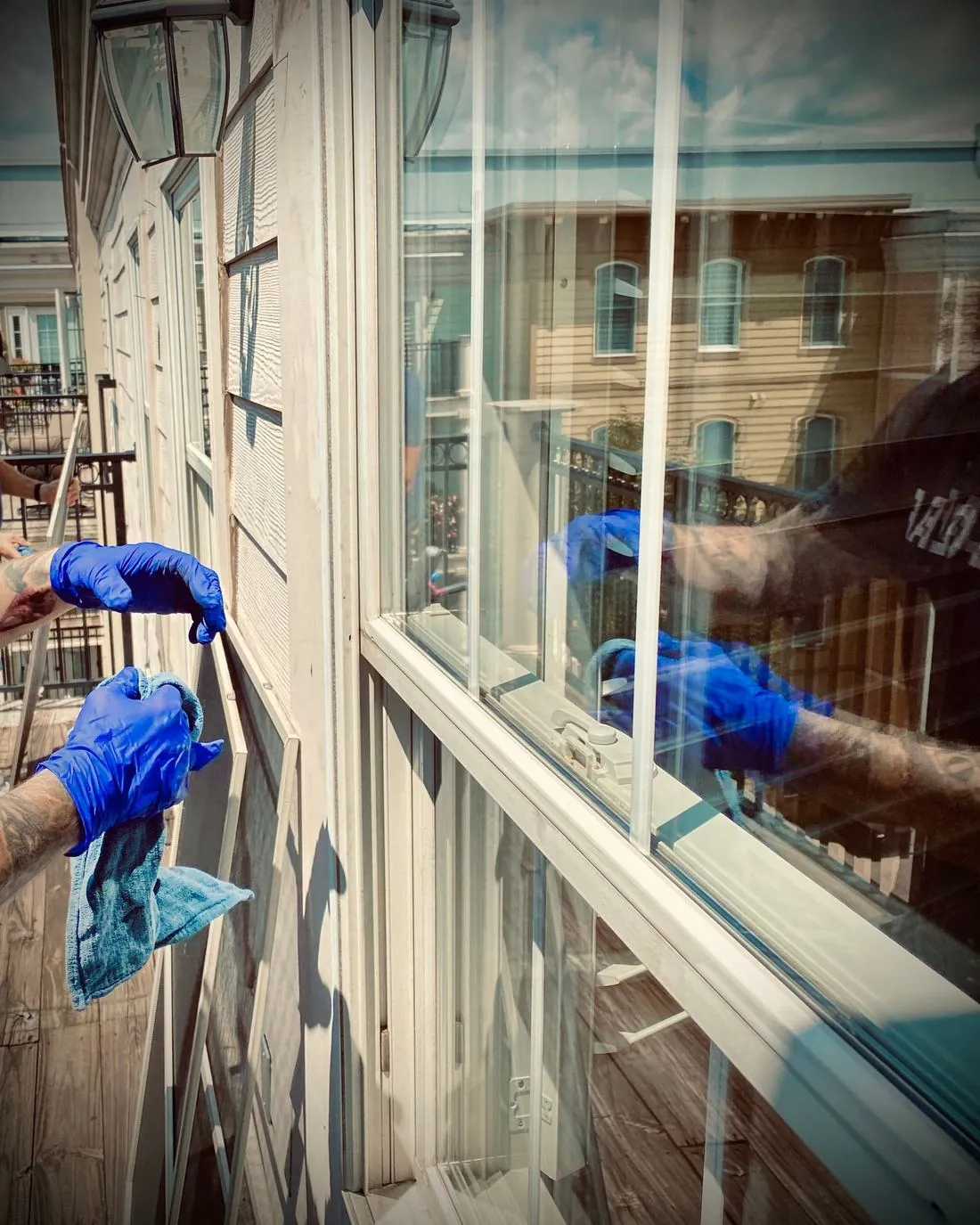 Gloved hands cleaning a storefront window from inside the shop